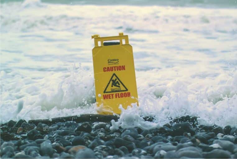 Caution sign in ocean waves on a beach in Bali, symbolizing travel safety concerns and natural risks