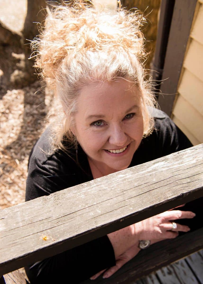 Anne McCormick leaning on a structure looking up at the camera