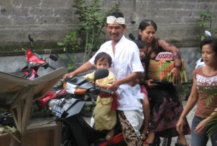 Balinese man with four kids on a motorcycle — a common sight that captures everyday life and things to do in Bali